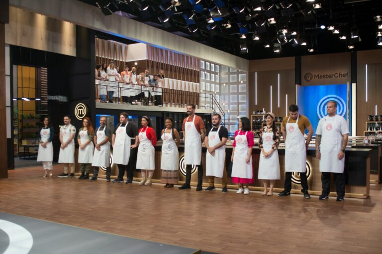 Imagem com os 13 eliminados da temporada do MasterChef Brasil lado a lado na cozinha do programa