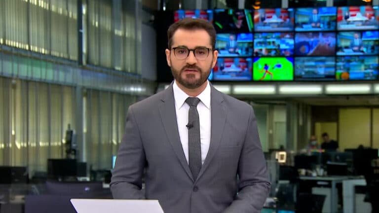 Imagem com foto do jornalista Marcelo Cosme durante a apresentação do Jornal Hoje