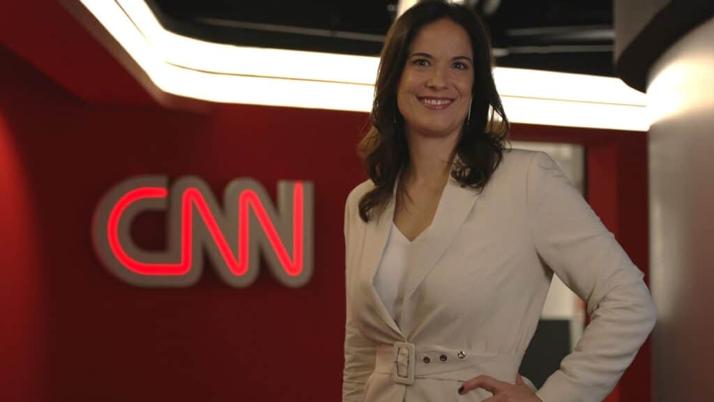 Foto de Clarissa Oliveira em frente ao logo da CNN Brasil