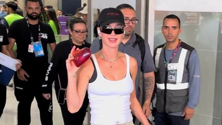 Foto de Katy Perry chegando de óculos escuros e coração na mão no Aeroporto do Galeão no Rio de Janeiro