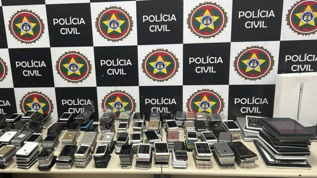 Foto de celulares supostamente roubados no Rock in Rio em frente a banner da Polícia Civil