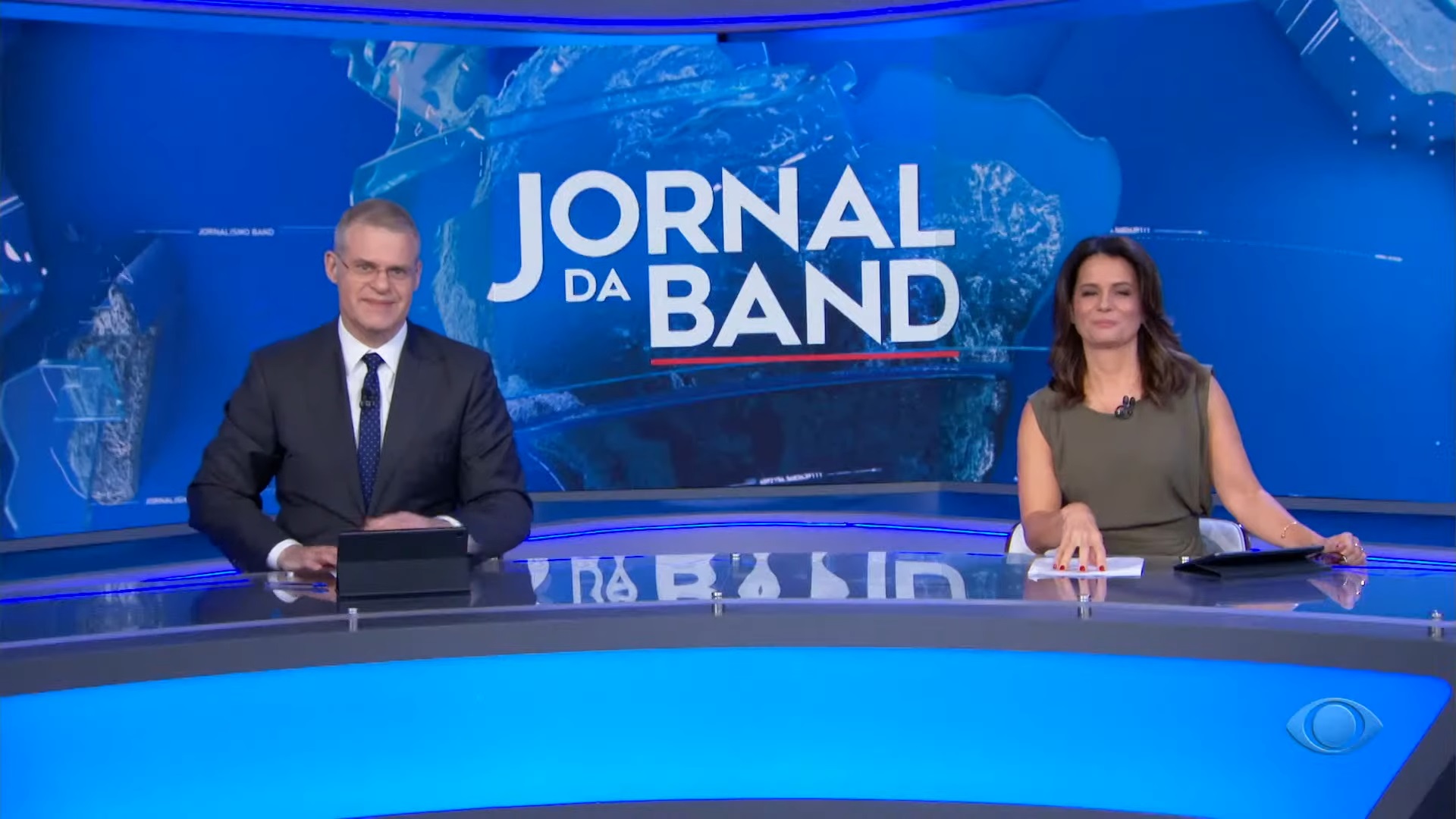 Foto de Eduardo Oinegue e Adriana Araújo apresentando o Jornal da Band