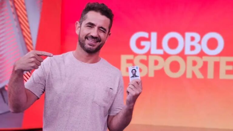 Foto de Felipe Andreoli segurando crachá da Globo no estúdio do Globo Esporte