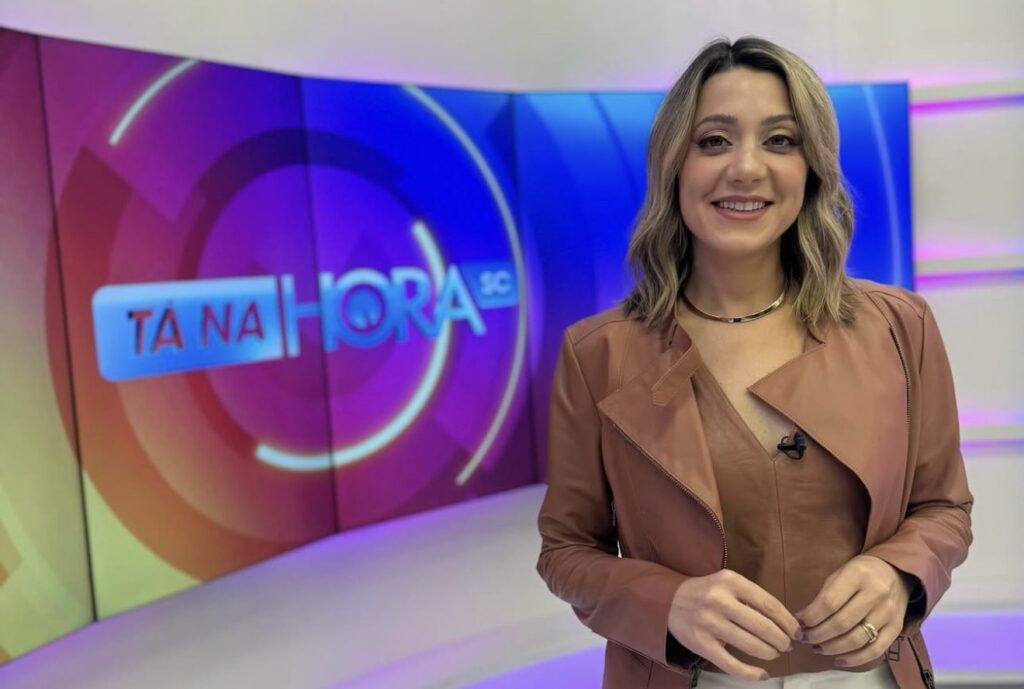 A imagem mostra a jornalista Gabrielle Ravasco no estúdio do programa Tá na Hora SC