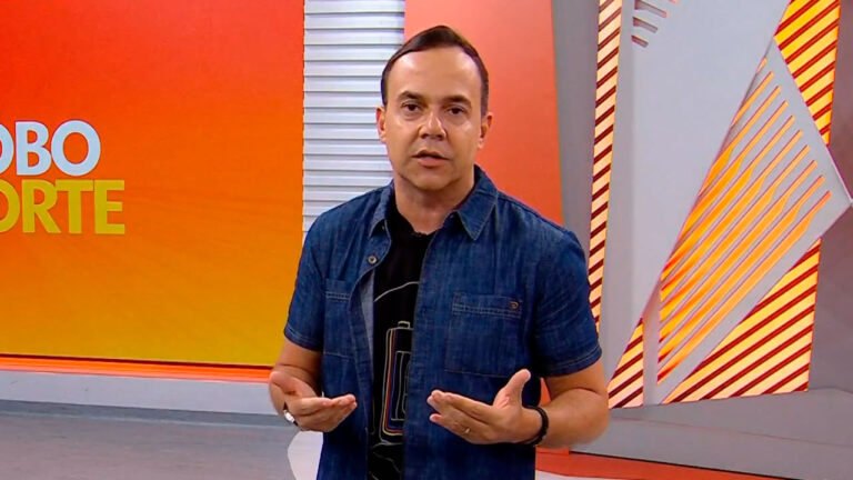 Tiago Medeiros no estúdio do Globo Esporte Pernambuco, gesticulando enquanto apresenta o programa, com cenário laranja ao fundo