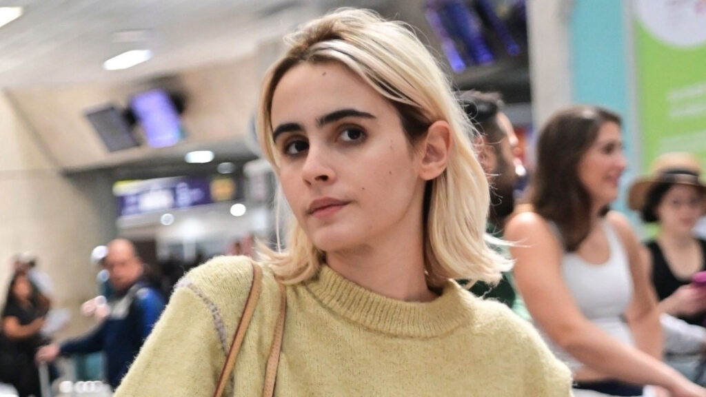 Valentina Herszage é fotografada no aeroporto do Rio de Janeiro, vestindo um suéter amarelo claro e carregando uma bolsa, após participar da cerimônia do Oscar