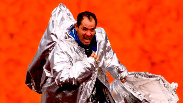 Clayton Conservani usando traje térmico dentro da cratera do vulcão Marum com lava ao fundo