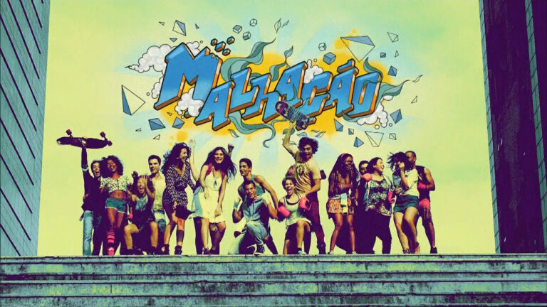 Elenco de Malhação 2014 posa animado em escadaria com logo da novela ao fundo em grafite colorido