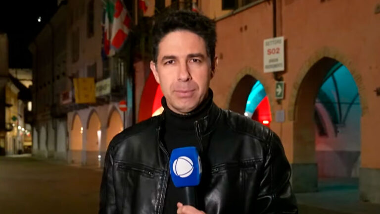 Mauro Júnior segura microfone da Record durante entrada reportagem sobre a morte do papa Francisco em rua do Vaticano iluminada à noite
