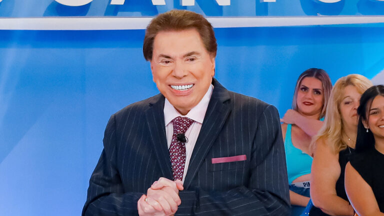 Silvio Santos sorrindo no palco de seu programa no SBT com plateia feminina ao fundo