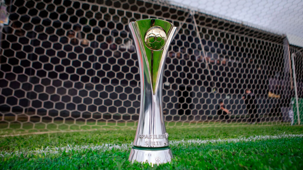 Taça da Série C do Campeonato Brasileiro posicionada no gramado em frente à rede do gol