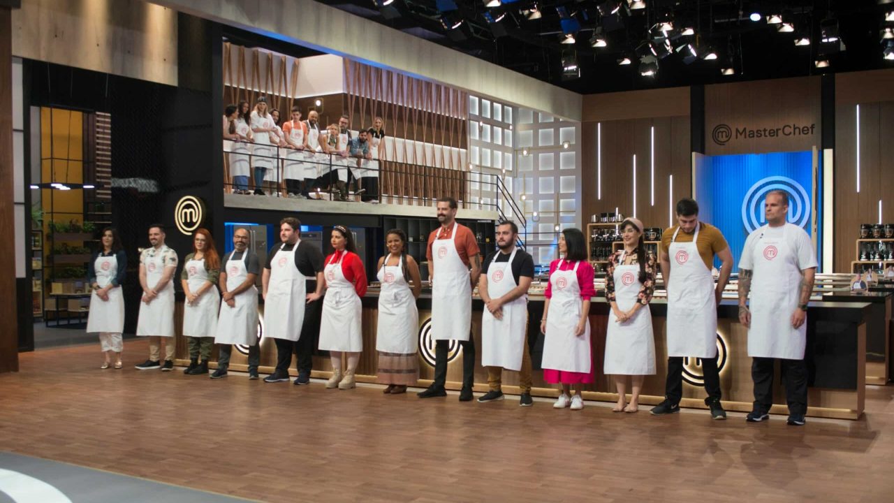 Imagem com os 13 eliminados da temporada do MasterChef Brasil lado a lado na cozinha do programa