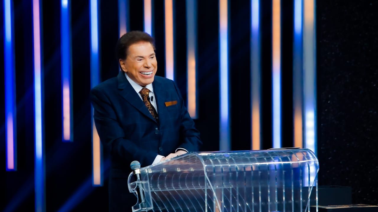 Imagem com foto de Silvio Santos sorrindo no púlpito do cenário do Troféu Imprensa 2022, gravado nos estúdios do SBT