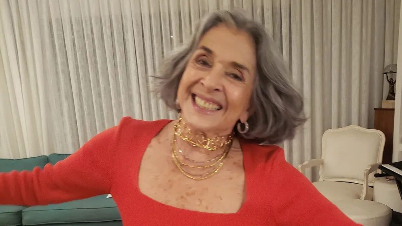 Betty Faria sorridente, vestindo uma roupa vermelha, com os braços abertos