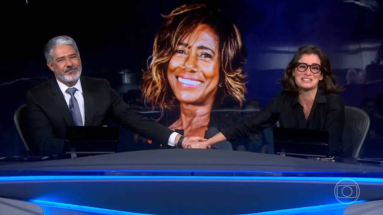 Foto de William Bonner e Renata Vasconcelllos homenageando Glória Maria na bancada do Jornal Nacional