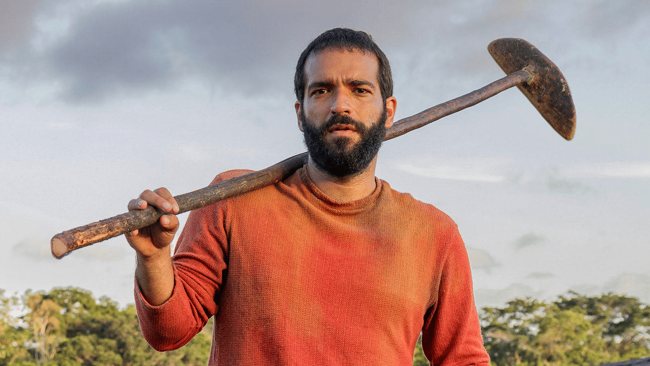 Humberto Carrão como o protagonista José Inocêncio na primeira fase da novela Renascer. Ele aparece com uma enxada no ombro