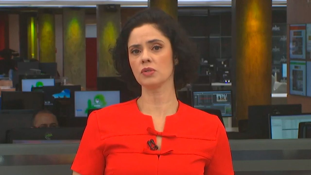 Juliana Castanha apresentando o Bom Dia Ceará, da TV Verdes Mares, afiliada da Globo, usando blazer vermelho, com a redação da emissora ao fundo