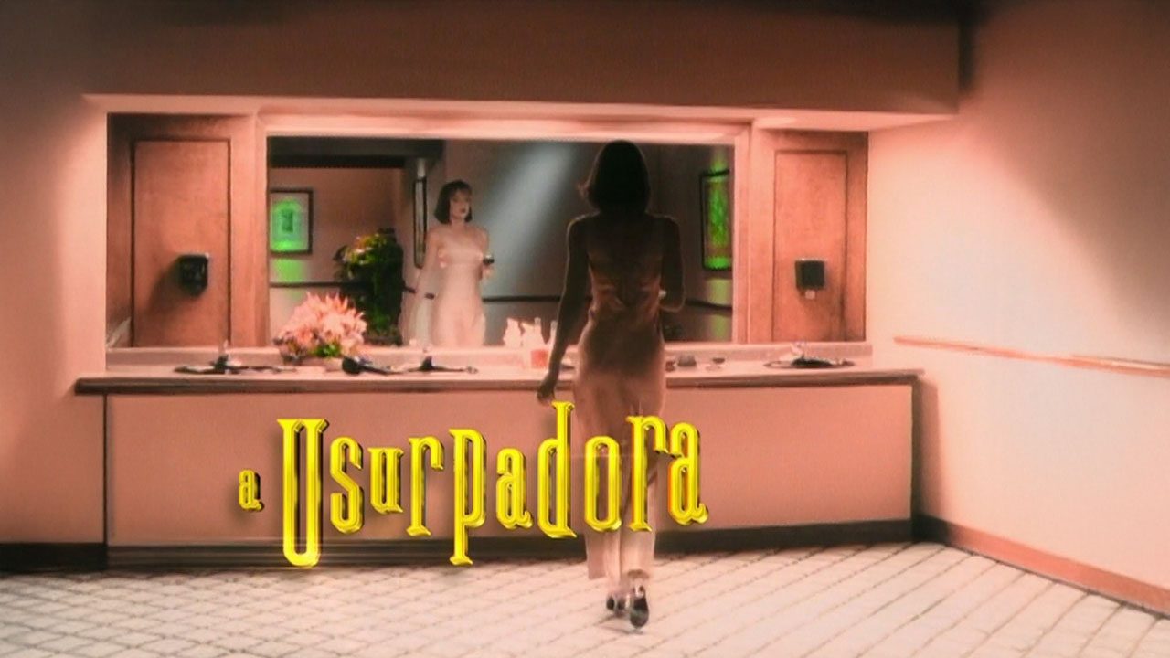 Cena de abertura da novela A Usurpadora com Paola Bracho de vestido claro caminhando em direção a um espelho, onde sua imagem refletida aparece diferente, e o logotipo da novela em destaque