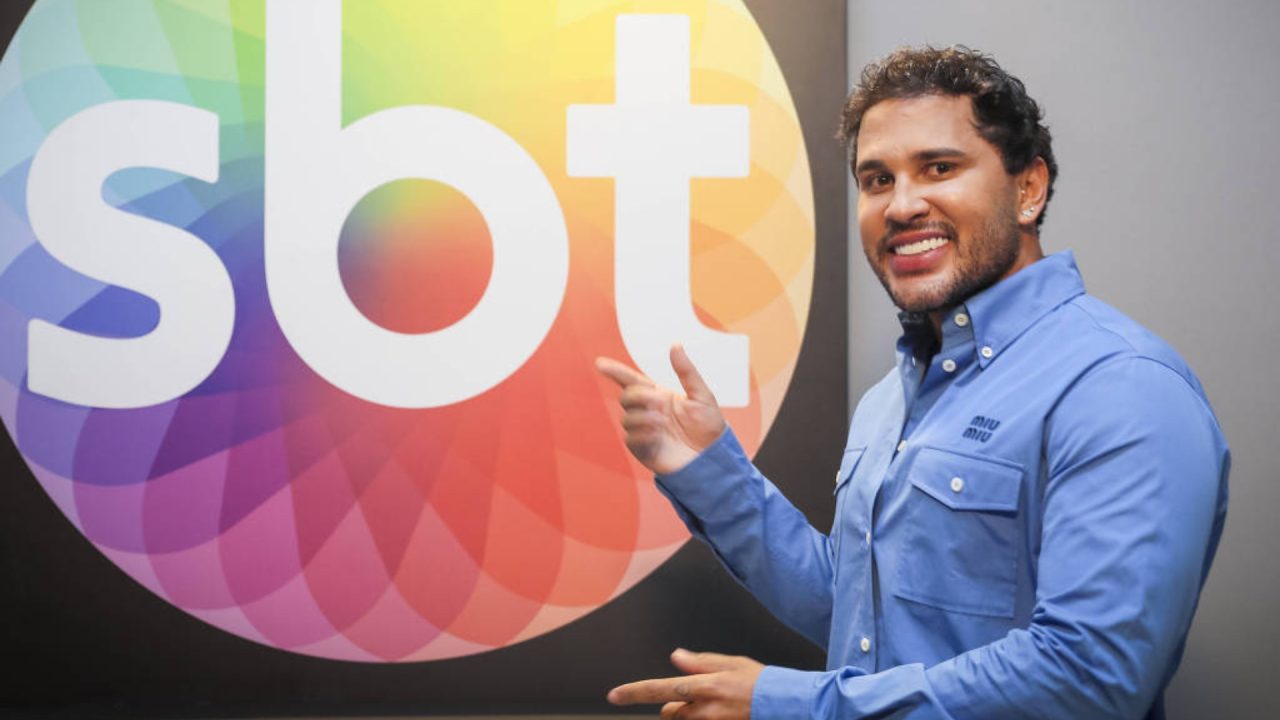 Foto de Lucas Guimarães em frente a logo do SBT