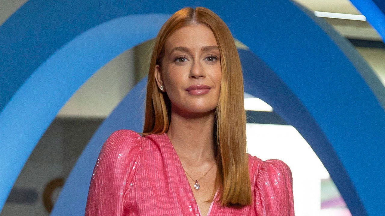 Cotada para protagonizar a nova novela de Aguinaldo Silva na Globo, Marina Ruy Barbosa em evento, usando vestido rosa brilhante e posando diante de uma estrutura azul