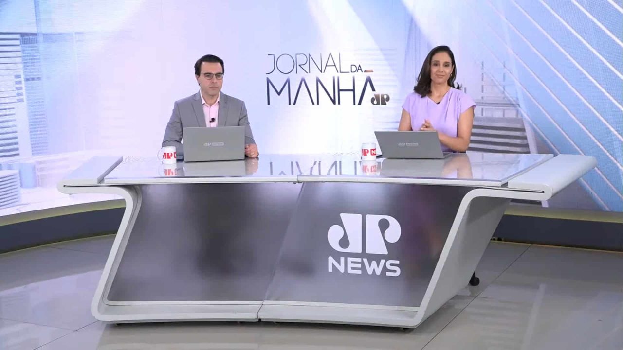 Foto de Rafael Colombo e Lívia Zanolini na bancada do Jornal da Manhã, da Jovem Pan