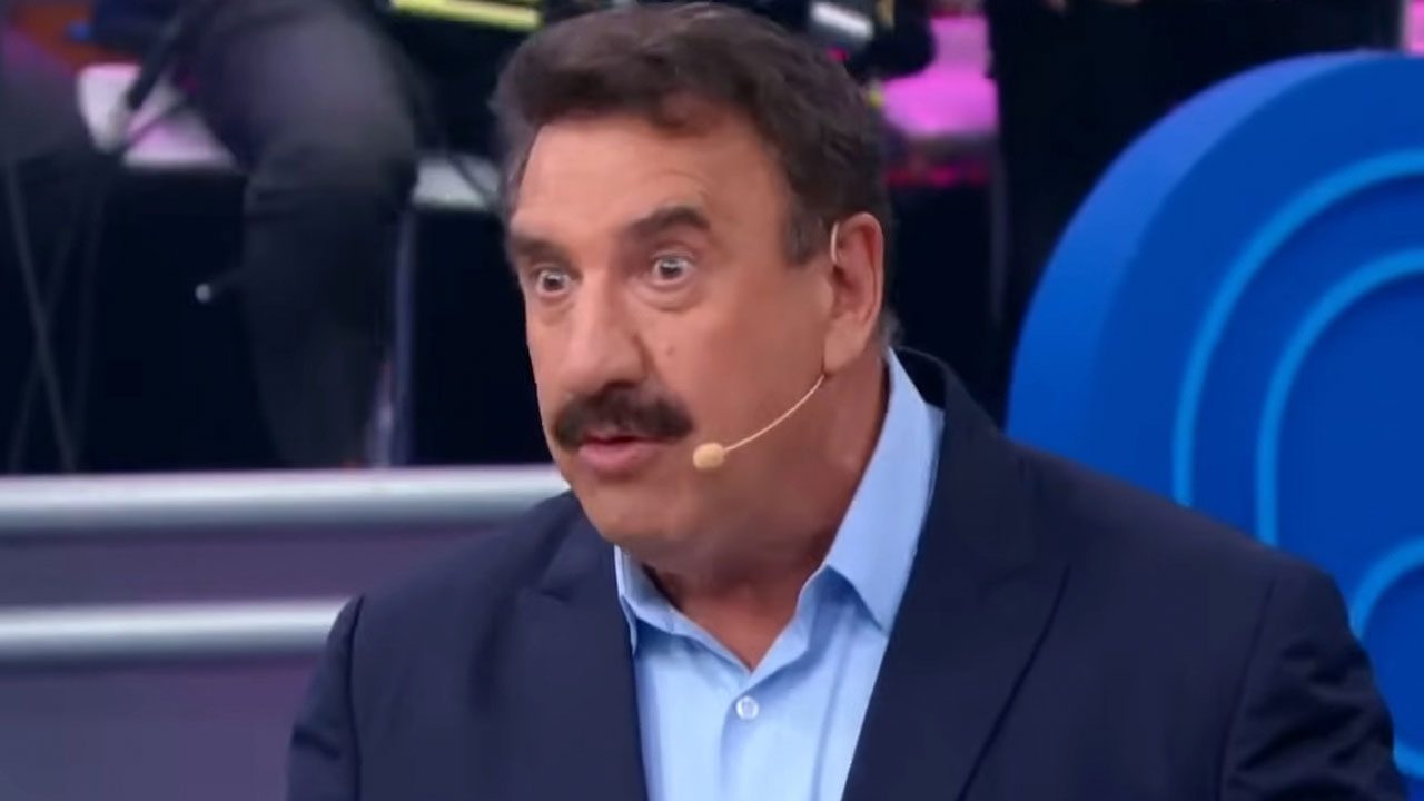 Ratinho durante apresentação do Programa do Ratinho no SBT usando paletó azul e microfone de lapela no palco