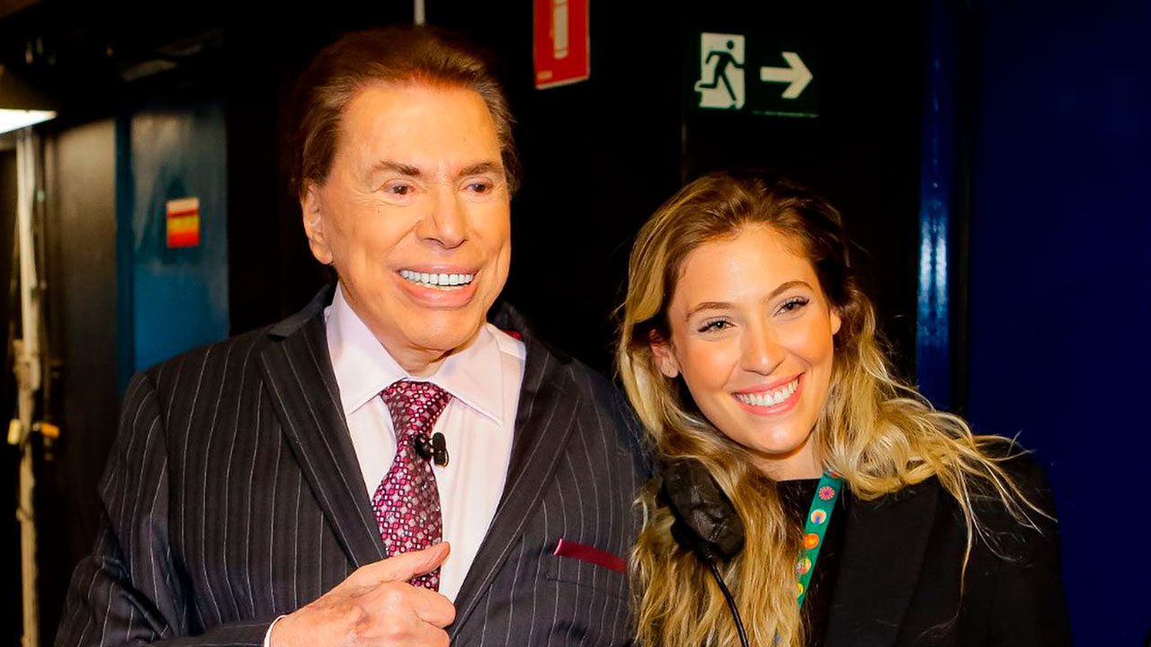 Silvio Santos sorrindo ao lado da produtora Mayara Mattar nos bastidores do Programa Silvio Santos