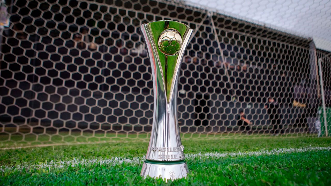 Taça da Série C do Campeonato Brasileiro posicionada no gramado em frente à rede do gol